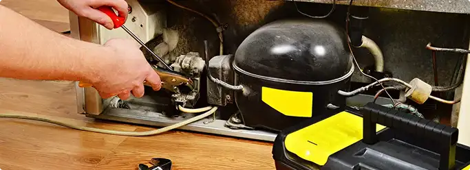 Refrigerator repair technician fixing the compressor and wiring in Phoenix, AZ