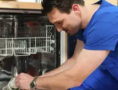 Dishwasher repair technician inspecting and servicing an open dishwasher in Chandler, AZ