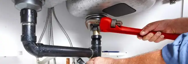 Garbage disposal repair technician tightening the sink drain and disposal connection in Chandler, AZ