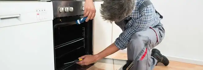 Oven repair technician inspecting and servicing an electric oven in Chandler, AZ