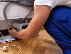 Appliance repair technician fixing refrigerator water line and connections in Chandler, AZ